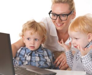 Nanny with glasses teache little kids with computer